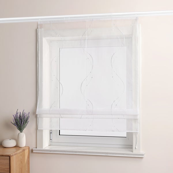 Fensterdekoration mit transparentem, weißem Stoffrollo mit Motiv vor einem Fenster.