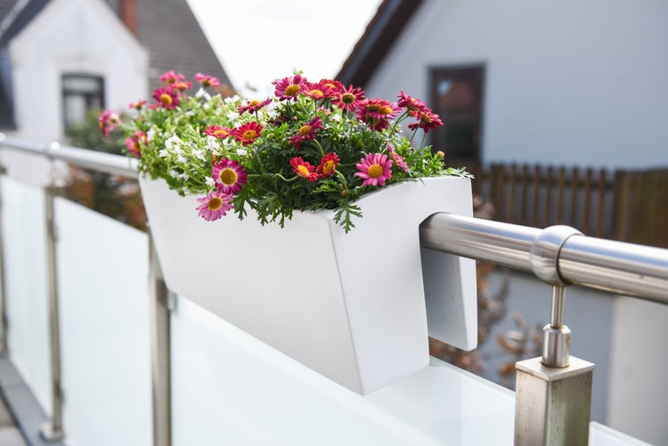 Weißer Balkonkasten mit bunten Blumen, montiert an einem runden Balkongeländer aus Edelstahl.