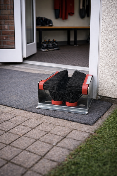 Schuhputzbürste vor einer Haustür auf einer Fußmatte