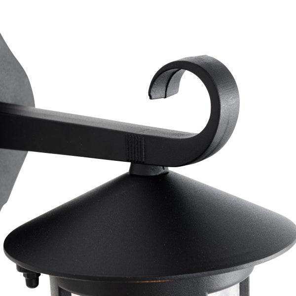 Detail einer schwarzen Außenwandleuchte aus Metall mit dekorativem geschwungenem Haltearm.