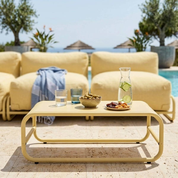 Niedriger Lounge-Tisch aus Metall mit abgerundetem Gestell in einer sonnigen Außenanlage am Pool mit Getränken und Snacks.