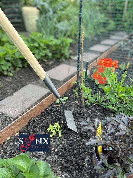 Gartenhacke mit Holzgriff im Einsatz in einem Gemüsebeet.
