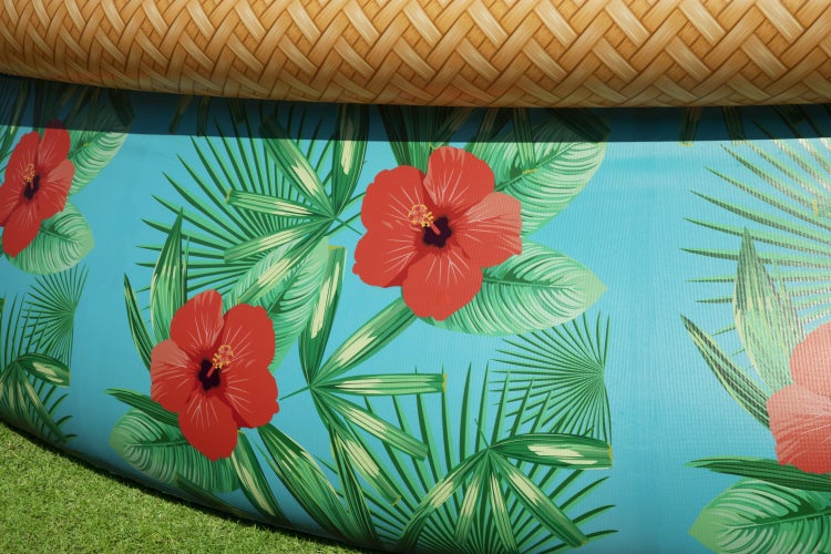 Nahaufnahme einer Poolwand mit tropischem Hibiskus- und Palmenblattmuster sowie einem oberen Rand in Rattanoptik.