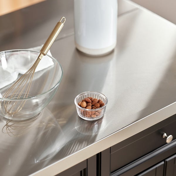 Küchenszene mit Rührschüssel, Schneebesen, Mandeln und Behälter auf einer Edelstahlfläche