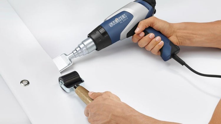 Steinel Heißluftgebläse HL 2020 E mit Flachstrahldüse und Andrückrolle beim Verschweißen einer Kunststoffplane.