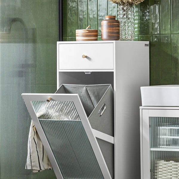 Badezimmer Szene mit einem weißen Badschrank inklusive Wäschekippe und Schublade. Auf der Ablage stehen drei Dekovasen.