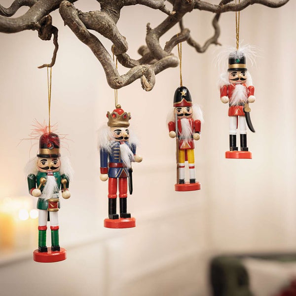 Dekorative Nussknackerfiguren aus Holz hängen an einem Ast als Weihnachtsdekoration.