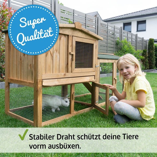 Hochwertiger Holz-Kleintierstall mit Freilaufgehege im Garten, stabiler Draht bietet Schutz für das weiße Kaninchen, ein Kind öffnet die Stalltür.