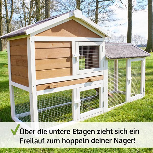 Zweistöckiger Kleintierstall aus braunem und weißem Holz mit integriertem Freilaufgehege auf der unteren Ebene im Freien auf einer Rasenfläche.