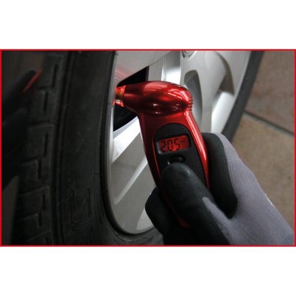 Ein Reifen wird mit einem digitalen Reifendruckmesser geprüft.