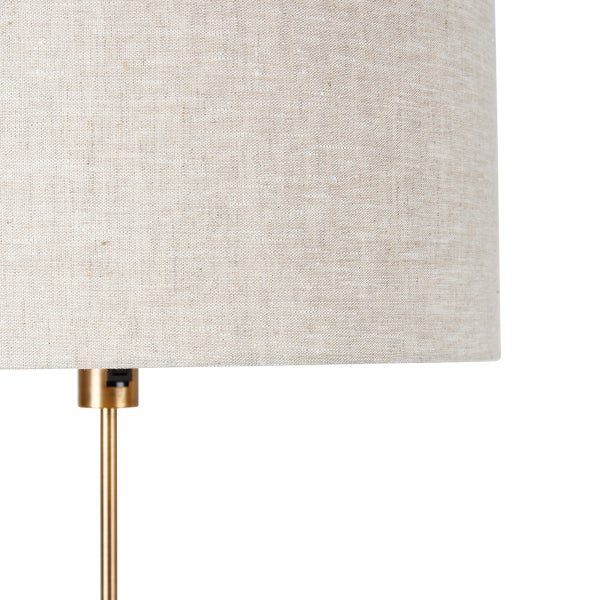 Detailaufnahme eines Lampenschirms aus Stoff mit goldfarbenem Lampenfuß.