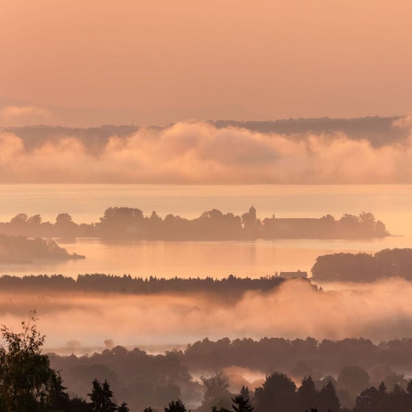 Landschaft mit See, Bäumen und Nebel