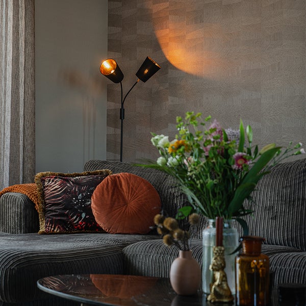 Wohnzimmer mit Sofa, Stehlampe und Blumenvase