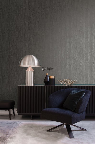 Wohnzimmer mit grauer Holzoptik-Tapete, Sessel, Kommode und Lampe