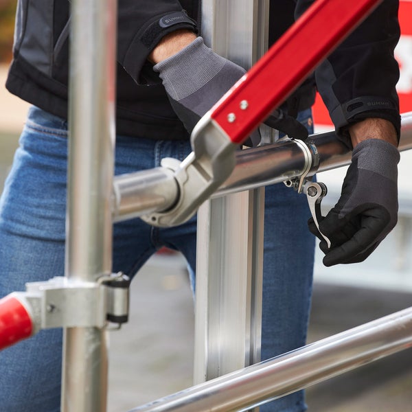 Person montiert ein Gerüst mit einem Schnellspanner.