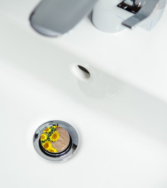 Waschbeckenstöpsel mit Sonnenblumenmotiv in einem weißen Waschbecken