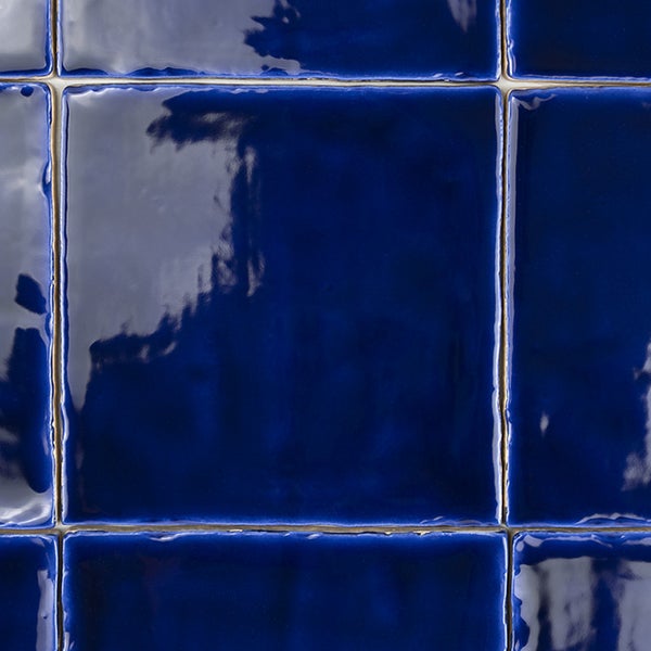 Quadratische Wandfliesen mit glänzender Oberfläche in Tiefblau als Fliesenverband verlegt