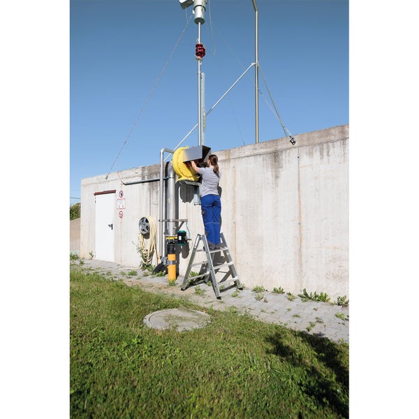 Frau auf einer Leiter, die an einer Lüftungsanlage arbeitet
