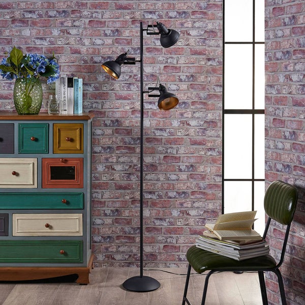 Stehleuchte mit drei Leuchten in einem Zimmer mit Ziegelwand