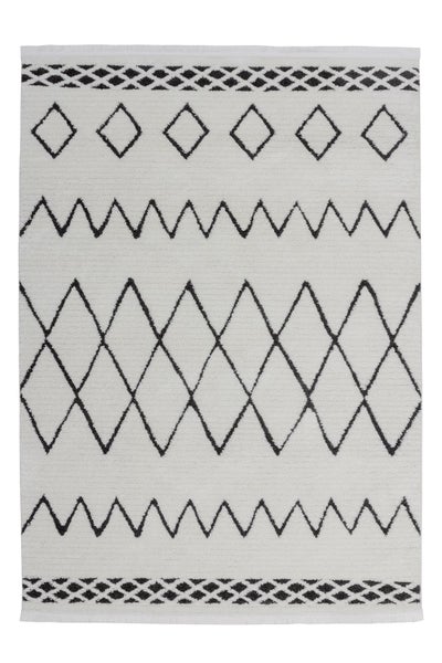 Weißer Teppich mit schwarzen geometrischen Mustern wie Zickzack-Linien und Rauten sowie Fransen an den Enden.