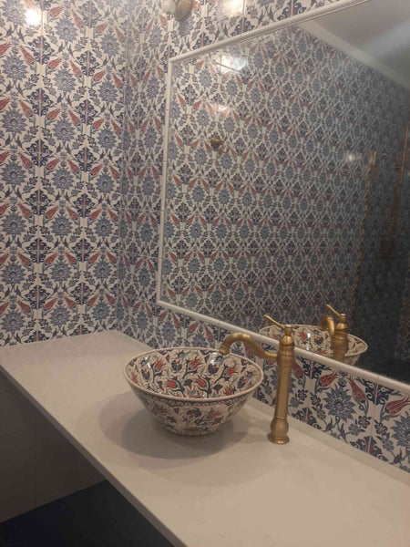 Badezimmer mit gemusterten Fliesen, Waschbecken und Spiegel