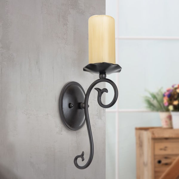 Wandkerzenhalter aus Metall mit dekorativem Schnörkeldesign und einer Stumpenkerze an einer Wand montiert