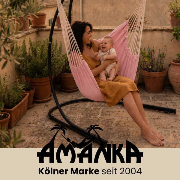 Mutter mit Baby in einer Hängematte mit Gestell auf einer Terrasse umgeben von Topfpflanzen. Amanka Logo.
