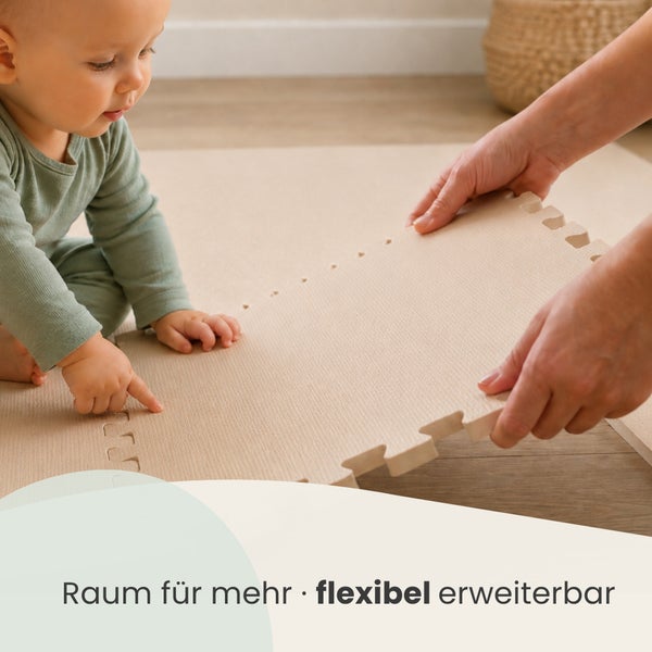 Ein Kleinkind und Hände einer erwachsenen Person verlegen eine flexible, erweiterbare Schaumstoff Puzzlematte für Kinder auf einem Boden.