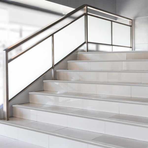 Moderne helle Treppe mit weißen Stufen und einem Geländer aus Edelstahl und Glasfüllung.