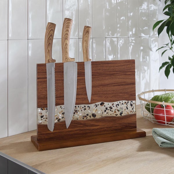 Magnetischer Messerblock aus Holz mit dekorativem Harzstreifen und drei Küchenmessern auf einer Küchenarbeitsplatte vor weißem Fliesenspiegel.