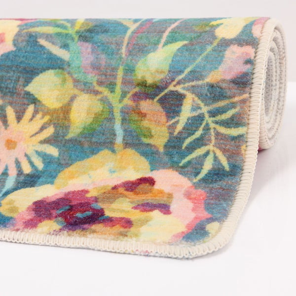 Gerollter Teppich mit buntem Blumenmuster in Aquarell-Optik und geketteltem Rand.