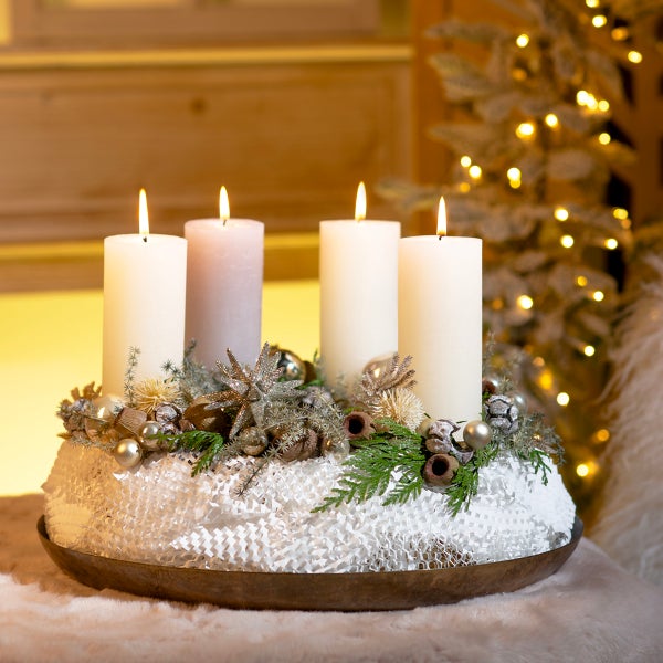 Adventskranz mit vier brennenden Kerzen, Sternen und Tannenzweigen auf einem Tisch