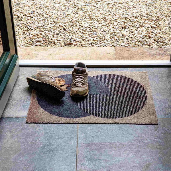 Fußmatte mit geometrischem Muster und Schuhen vor einer Terrassentür