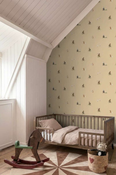 Kinderzimmer mit Tapete mit Tier und Fahrrad Motiven, Holzbett, Schaukelpferd und geflochtenem Korb auf Holzboden unter einer Dachschräge.