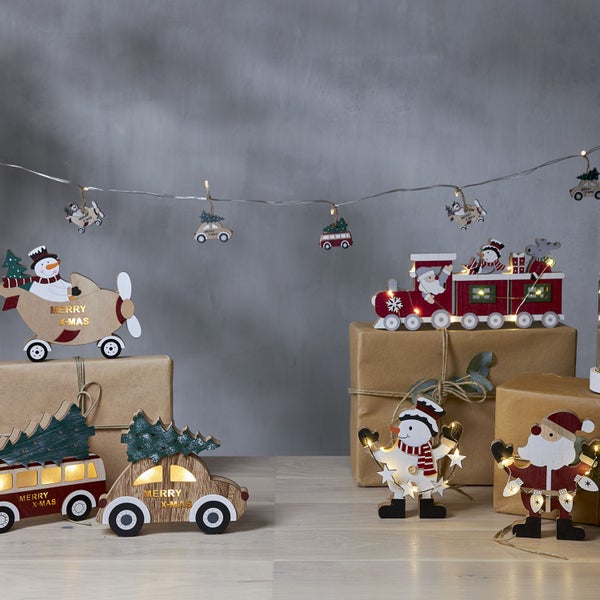 Weihnachtsdekoration mit Holzfiguren und Lichterkette auf Geschenken