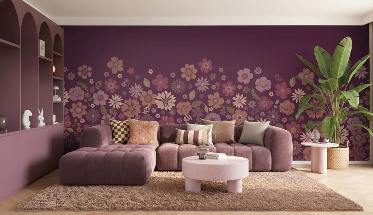 Wohnzimmer mit lila Couch, Couchtisch und Blumendekoration an der Wand