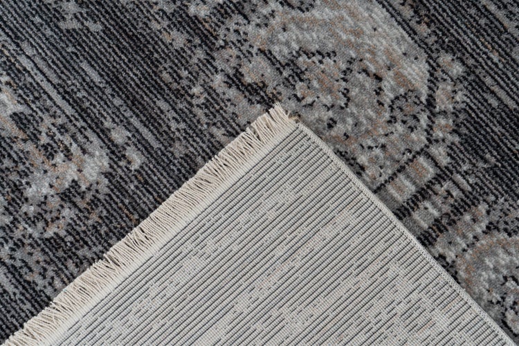 Nahaufnahme eines Teppichs im Vintage-Stil mit grauem Muster, gewebter Rückseite und kurzen Fransen.