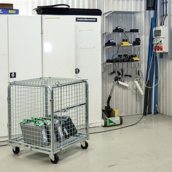 Gitterwagen mit Behältern in einer Lagerhalle.