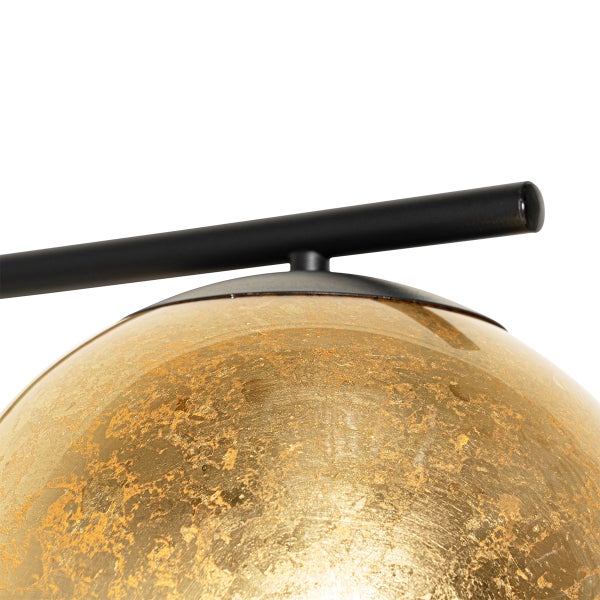 Detailaufnahme einer Leuchte mit goldenem Schirm und schwarzem Gestell