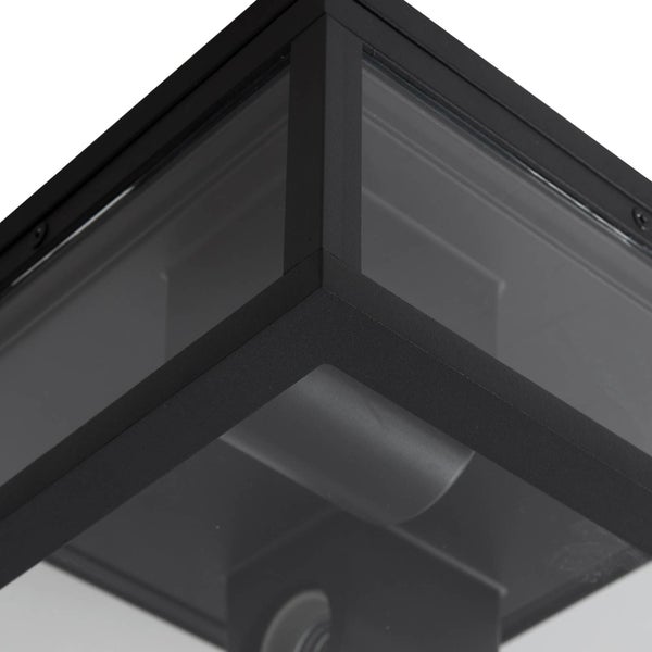 Nahaufnahme einer quadratischen Außenleuchte mit schwarzem Metallrahmen und klaren Glasscheiben.