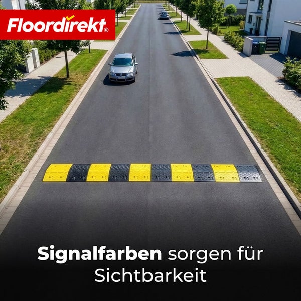 Floordirekt Logo. Gut sichtbare gelb-schwarze Fahrbahnschwelle auf einer asphaltierten Straße in einem hellen, organisierten Wohngebiet.