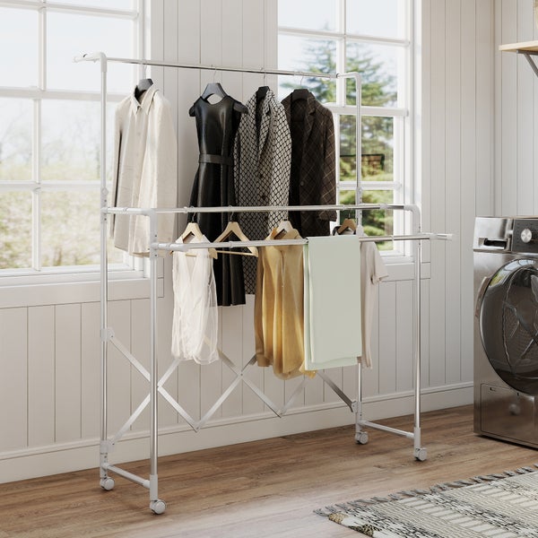 Mobiler, ausziehbarer Kleiderständer aus Metall mit Rollen in einer hellen Waschküche neben einer Waschmaschine.