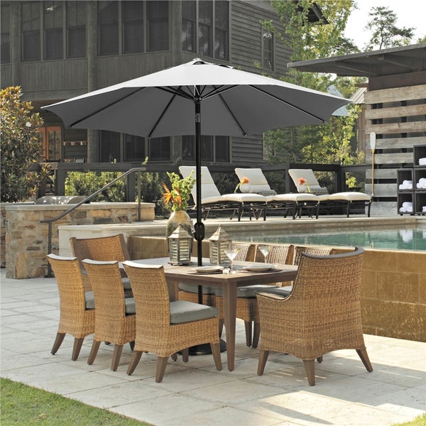 Gartenszene mit Esstisch, Stühlen und Sonnenschirm am Pool.