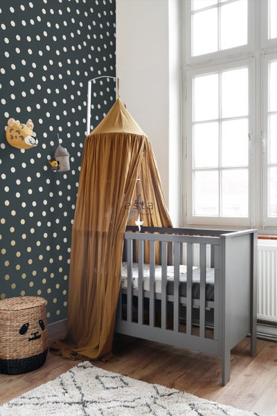 Kinderzimmer mit grauem Gitterbett, Baldachin, gepunkteter Tapete und Dekoration