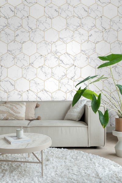 Wohnraum mit Sofa, Tisch und Wandtapete mit Marmormuster und goldenen Hexagonen