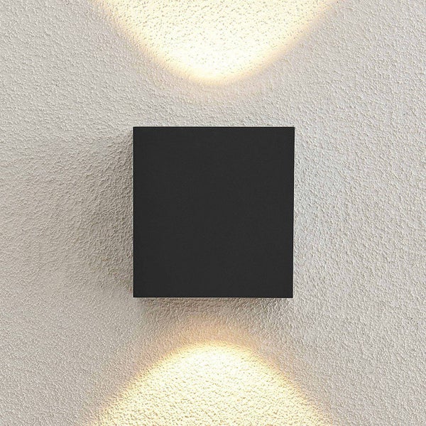 Quadratische LED-Außenwandleuchte in Schwarz mit Up-and-Down-Lichteffekt an einer strukturierten Wand.