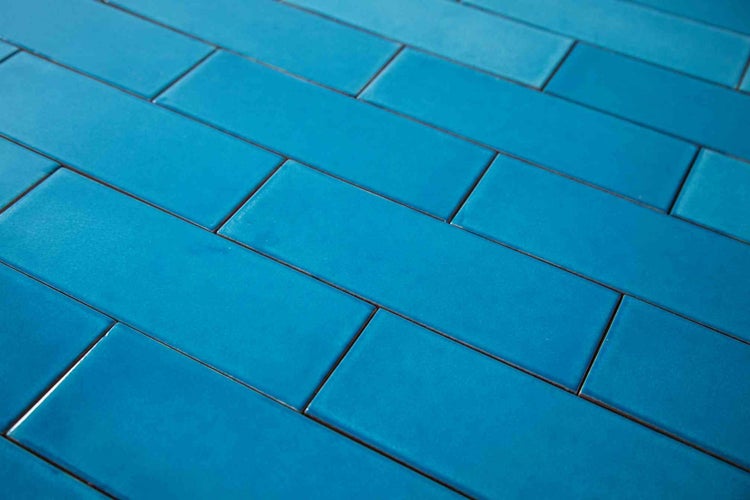 Blaue rechteckige Wandfliesen im Mauerverband mit glatter Oberfläche.