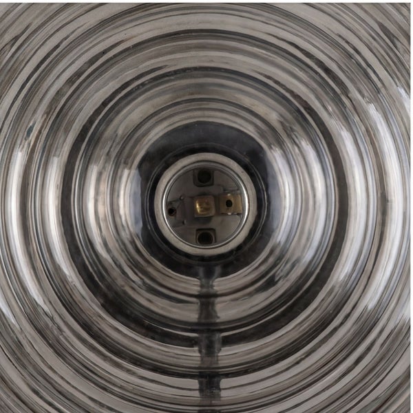 Nahaufnahme einer Leuchte mit einem geriffelten Glasschirm mit konzentrischen Ringen und einer zentralen Lampenfassung