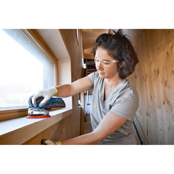 Frau schleift Holzrahmen mit einem Exzenterschleifer