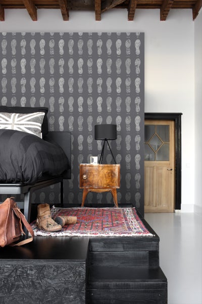 Schlafzimmer mit Bett, Nachttisch und Tapete mit Schuhabdruckmuster